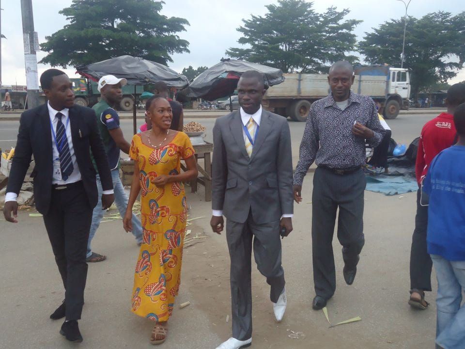 Team members walking through a market street with a local woman