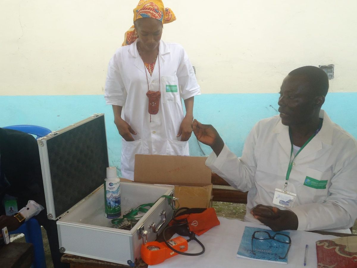Two volunteer medics at a table with a medical kit and blood pressure monitor