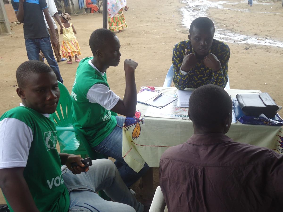 Young volunteers in green T-shirts registering people at a table outdoors