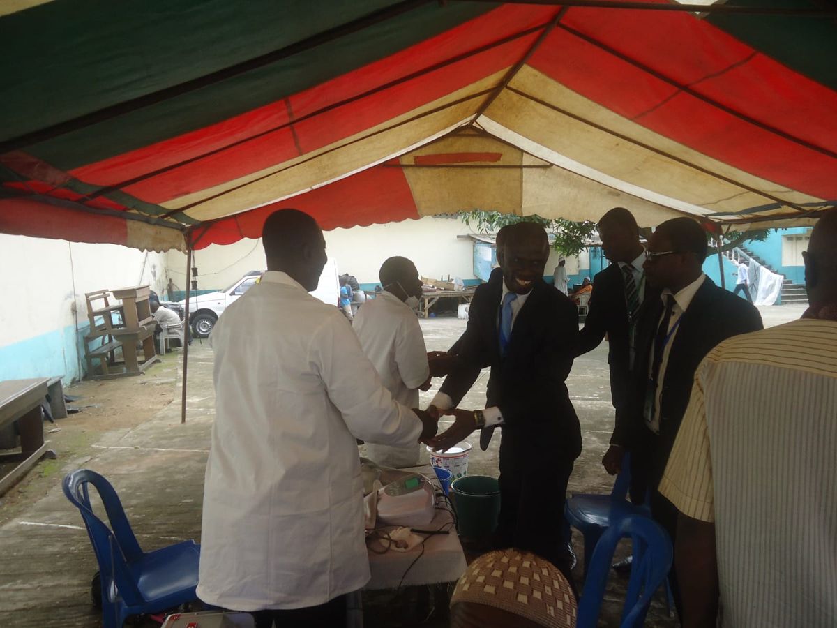 Volunteers in suits greeting medics under a red and white tent
